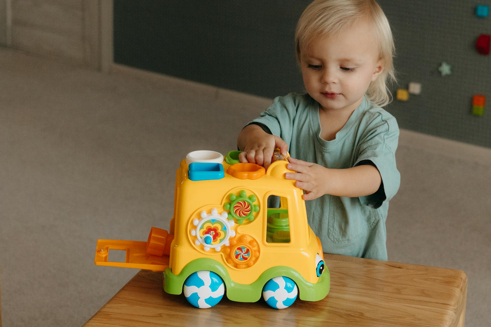Adorable toddler engaged with a vibrant educational toy, promoting fun learning indoors.